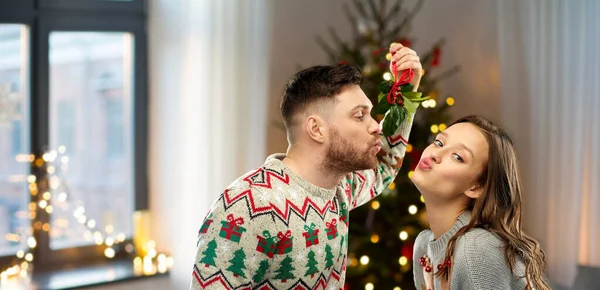 Pasangan bahagia berciuman di bawah mistletoe pada hari Natal Stok Lukisan  