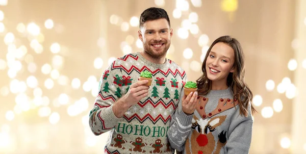 Pár s cupcakes v ošklivé vánoční svetry — Stock fotografie