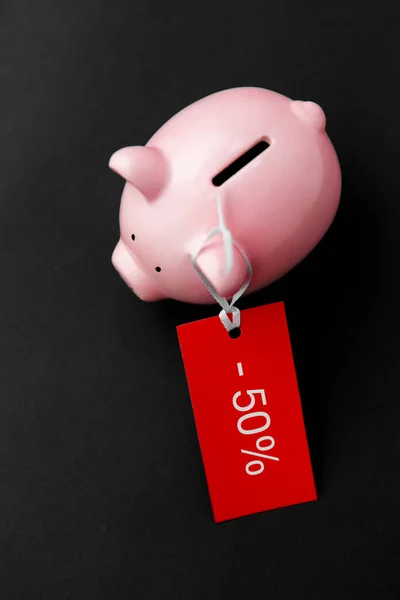 Piggy bank with red sale tag on black — Stock Photo, Image