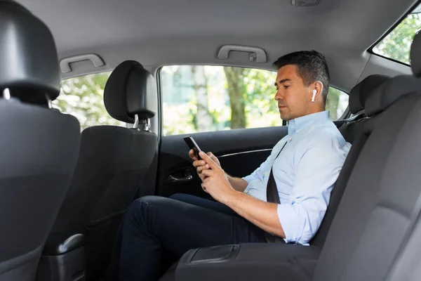 Passager avec écouteurs et téléphone portable en taxi — Photo