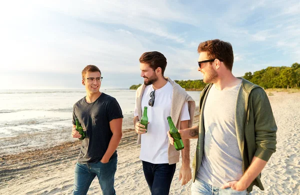 Mladí muži s nealkoholickým pivem kráčející po pláži — Stock fotografie