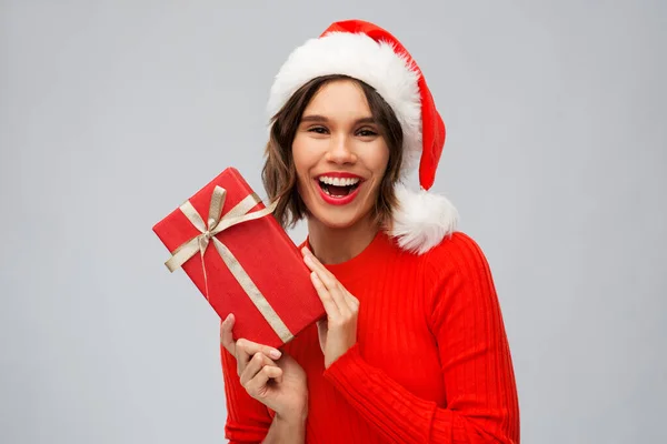 Felice giovane donna in cappello di Babbo Natale con scatola regalo rossa — Foto Stock