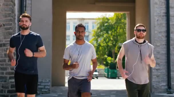 Amis masculins avec écouteurs courir à l'extérieur — Video