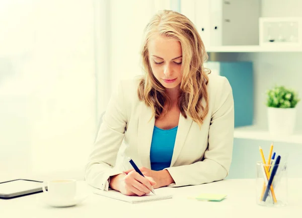 Business woman writing to notebook at office — стоковое фото