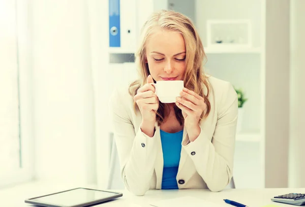 Счастливая деловая женщина пьет кофе в офисе — стоковое фото