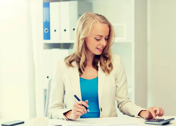 Businesswoman z kalkulatorem liczącym w biurze — Zdjęcie stockowe