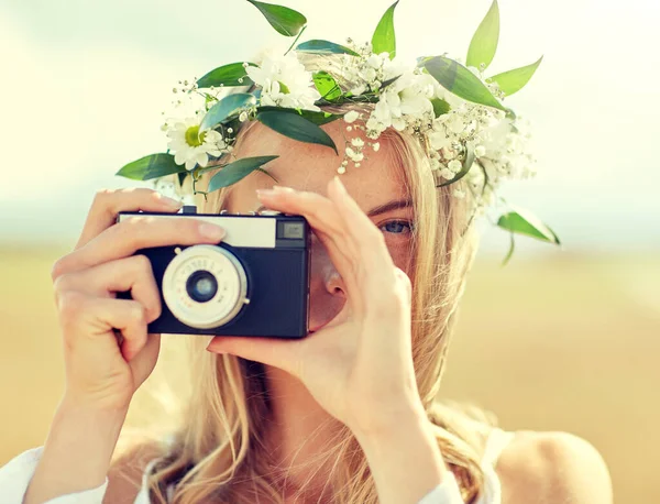 Gelukkig vrouw met film camera in krans van bloemen — Stockfoto