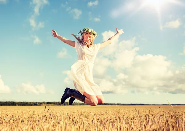 Lycklig kvinna i krans hoppa på spannmål fält — Stockfoto
