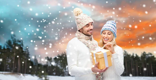 Χαμογελαστό ζευγάρι σε χειμωνιάτικα ρούχα με κουτί δώρου Εικόνα Αρχείου