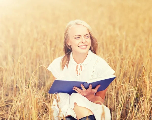 笑顔の若い女性は、穀物のフィールド上の本を読んで — ストック写真