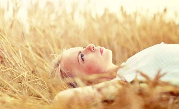 Mujer joven acostada en el campo de cereales y soñando —  Fotos de Stock