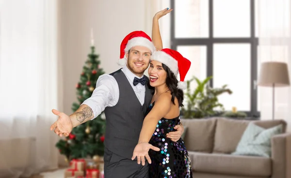 Glückliches Paar in Weihnachtsmützen zu Hause an Weihnachten — Stockfoto