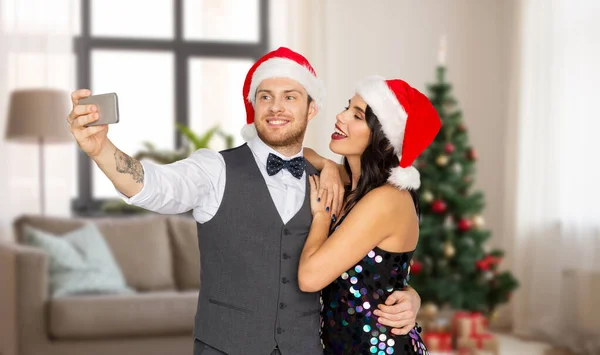 Pareja en santa sombreros tomando selfie en navidad —  Fotos de Stock