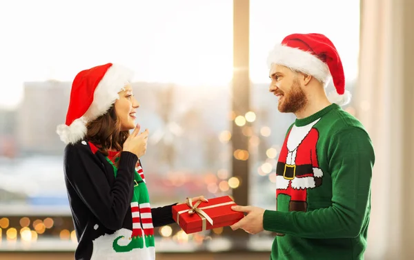 Casal feliz em camisolas de Natal com caixa de presente — Fotografia de Stock