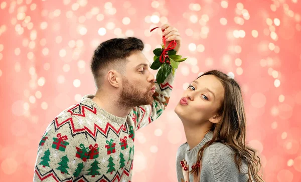 Счастливая пара целуется под омелой на Рождество — стоковое фото