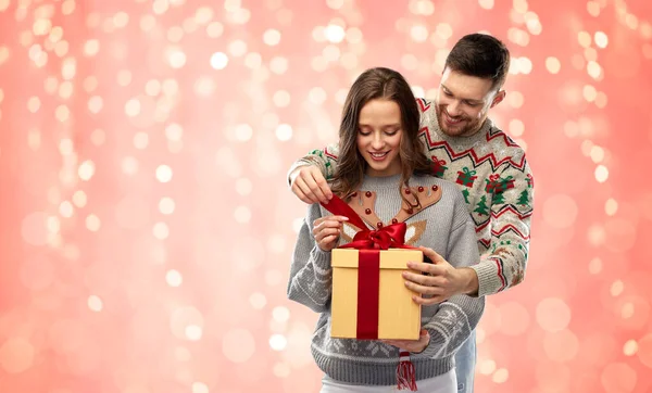Boldog pár karácsonyi pulóverben ajándékdobozzal — Stock Fotó