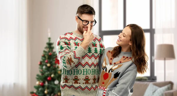 Happy couple in christmas ugly sweaters at home — Stock Photo, Image