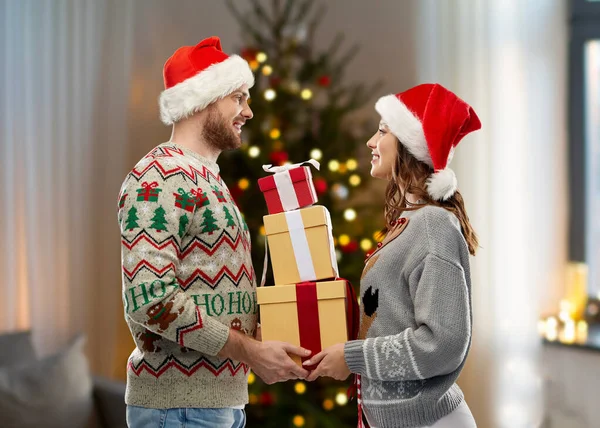 Casal em camisolas de Natal com presentes em casa — Fotografia de Stock