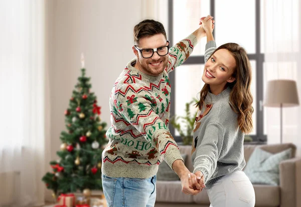 Pareja bailando en navidad feos suéteres en casa Imagen de archivo