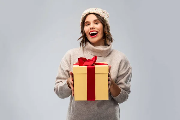 Jonge vrouw in gebreide winter hoed houden geschenkdoos — Stockfoto