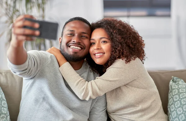 Casal feliz com smartphone levando selfie em casa — Fotografia de Stock