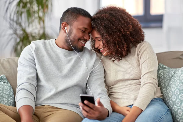 Feliz pareja con smartphone y auriculares en casa — Foto de Stock