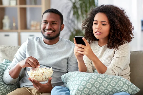 Casal africano com pipocas assistindo tv em casa — Fotografia de Stock