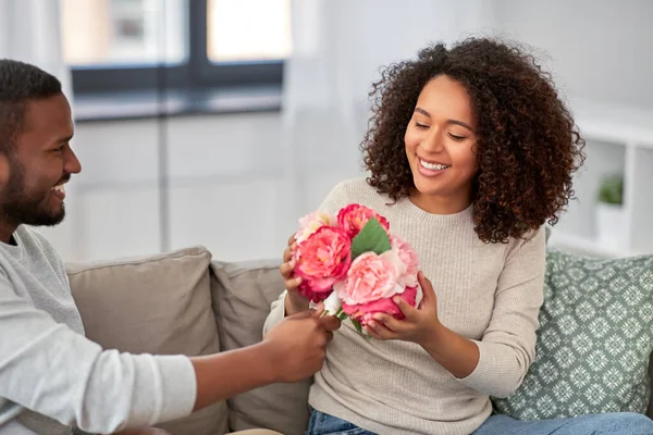 Happy couple with bunch of flowers at home — Stock Photo, Image