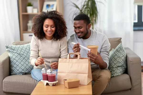 Happy couple with takeaway food and drinks at home — Stock Photo, Image