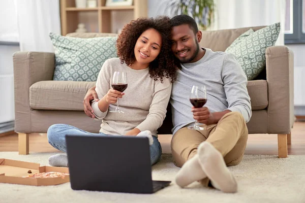 Счастливая пара с ноутбуком пить красное вино дома — стоковое фото