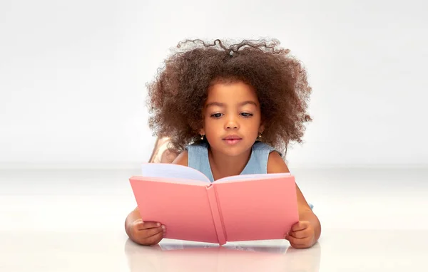 Lykkelig liten, afrittisk jente leser bok – stockfoto