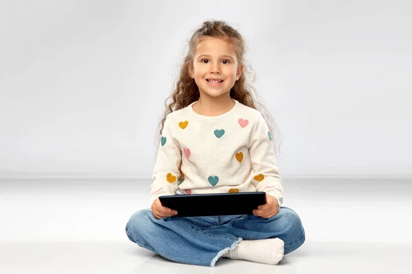 Menina sorridente com tablet computador sentado no chão — Fotografia de Stock