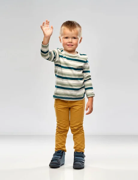 Menino em camisa listrada acenando mão — Fotografia de Stock