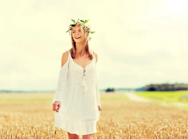 Счастливая молодая женщина в цветочном венке на зерновом поле — стоковое фото