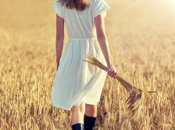 Giovane donna con spighette di cereali che camminano sul campo — Foto Stock