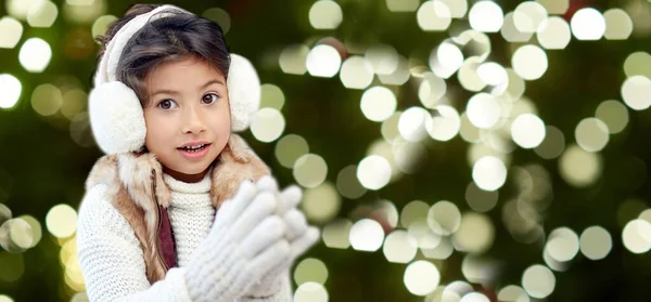 Happy little girl in earmuffs over winter forest — Stock Photo, Image