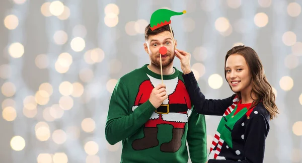 Cuplu cu recuzită de Crăciun în pulovere urâte — Fotografie, imagine de stoc