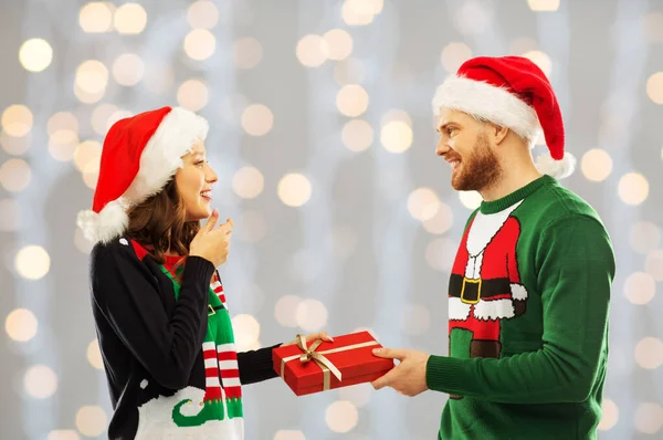 Happy couple in christmas sweaters with gift box — Stock Photo, Image