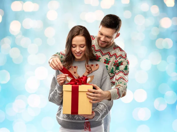 Щаслива пара в різдвяних светрах з подарунковою коробкою — стокове фото