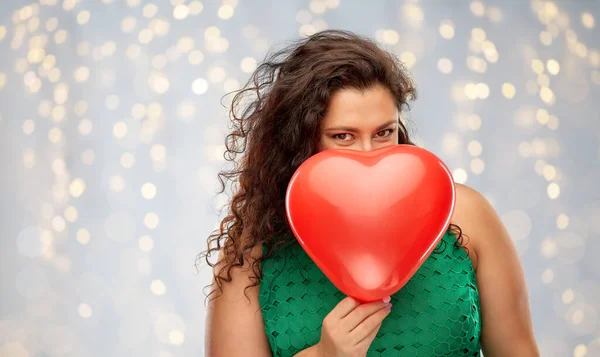 Mujer juguetona sosteniendo globo en forma de corazón rojo — Foto de Stock