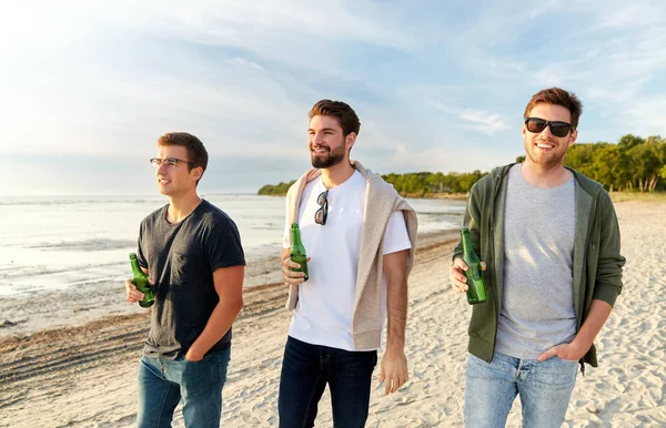 Young men with non alcoholic beer walking on beach — Stock Photo, Image