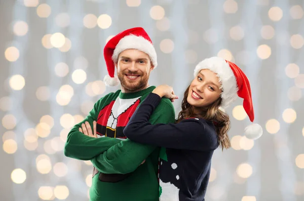 Feliz pareja en suéteres de Navidad y sombreros de santa —  Fotos de Stock