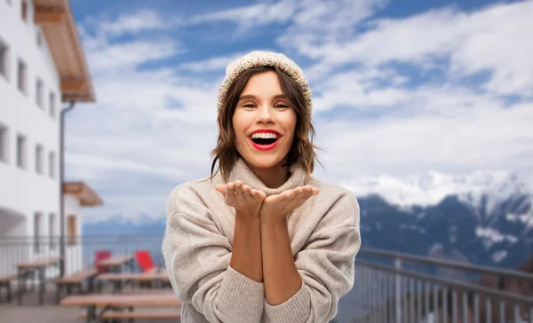 Kobieta w czapce zimowej wysyłając pocałunek powietrza w ośrodku narciarskim — Zdjęcie stockowe