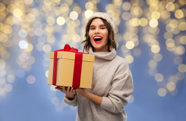 Young woman in winter hat holding christmas gift — Stock Photo, Image