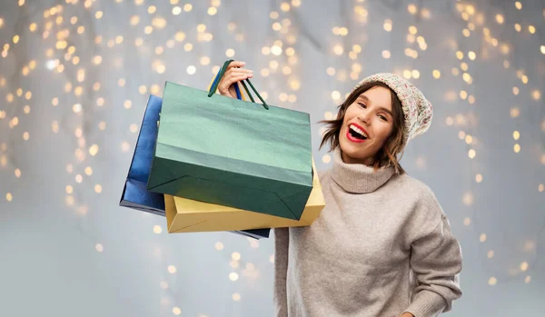 Jovem mulher de chapéu com sacos de compras no Natal — Fotografia de Stock