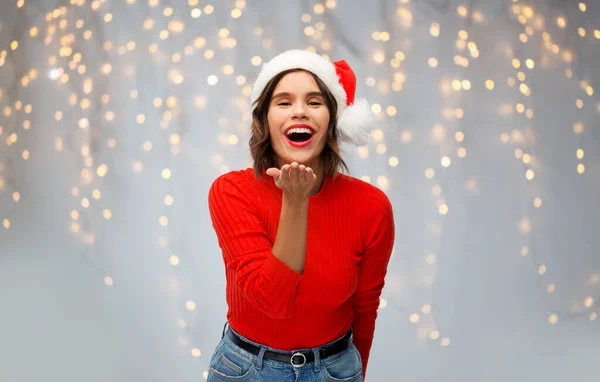 Kvinna i tomte hatt skicka luft kyss på jul — Stockfoto