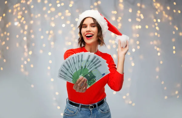 Щаслива жінка в капелюсі Санта з грошима на Різдво — стокове фото