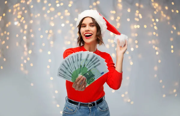 Happy woman in santa hat with money on christmas — Stock Photo, Image