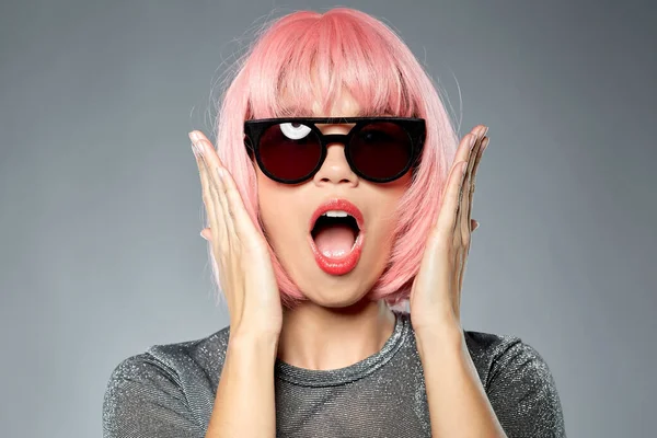 Femme heureuse en perruque rose et lunettes de soleil noires — Photo