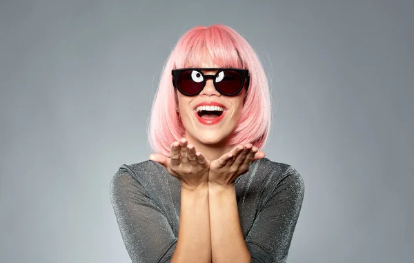 Mujer feliz en peluca rosa sosteniendo algo en las palmas de las manos —  Fotos de Stock